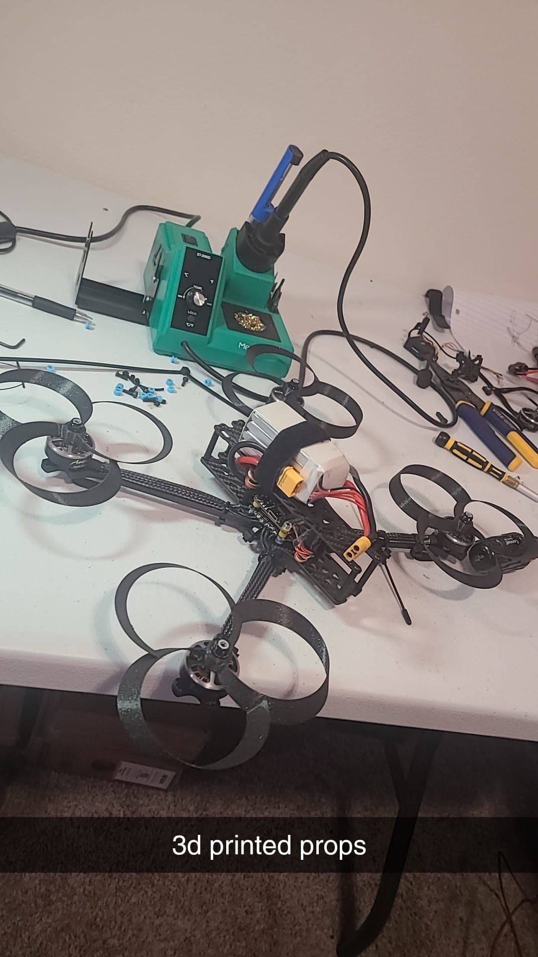 Custom-built FPV drone with 3D-printed propellers on the workbench